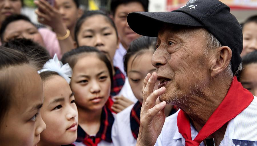 5月19日，周火生老人（前右）与金寨县希望小学的孩子们在一起交谈。当日，80多岁的周火生再次来到大别山腹地的安徽省金寨县南溪镇，开始了他的第100次金寨助学之旅。