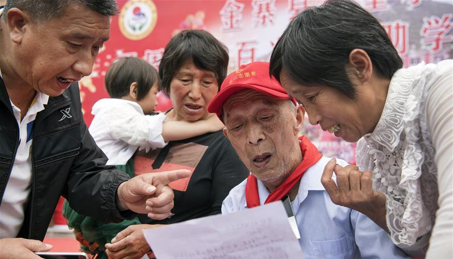 5月19日，周火生老人（右二）在阅读受助孩子从远方发来的感谢信。